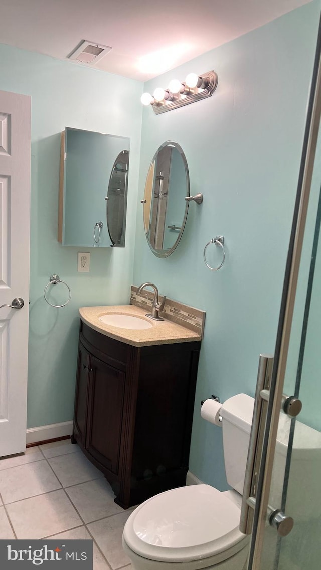 bathroom with toilet, vanity, baseboards, visible vents, and tile patterned floors