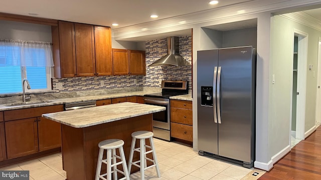 kitchen with decorative backsplash, wall chimney exhaust hood, appliances with stainless steel finishes, a center island, and a sink