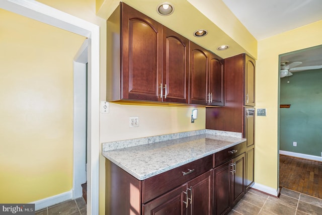 kitchen featuring dark tile patterned floors, ceiling fan, and light stone counters