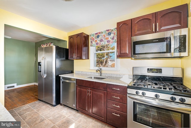 kitchen with light stone counters, sink, light tile patterned floors, and stainless steel appliances