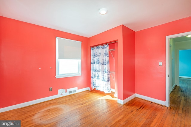 empty room featuring baseboards, visible vents, and hardwood / wood-style floors