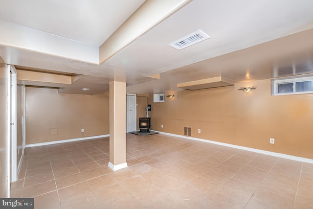 basement with light tile patterned floors and a wood stove