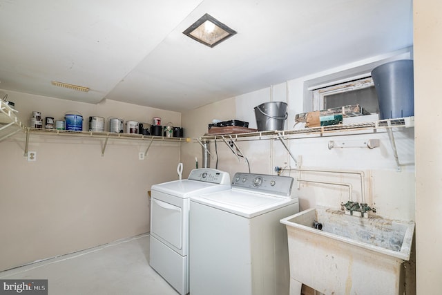 washroom featuring laundry area, separate washer and dryer, and a sink