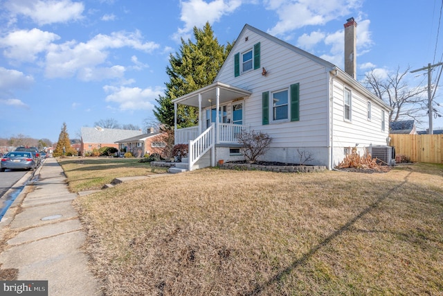 view of front of house with cooling unit, a porch, and a front lawn