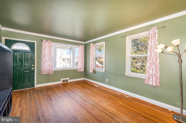 foyer featuring crown molding, hardwood / wood-style flooring, visible vents, and baseboards