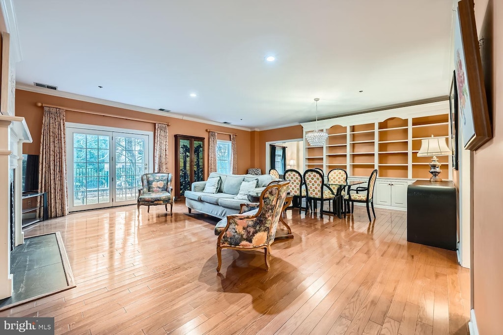 living room featuring crown molding, a chandelier, and light wood-type flooring