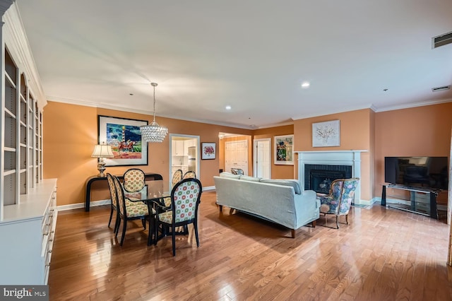 dining room with crown molding, a fireplace, and light hardwood / wood-style floors