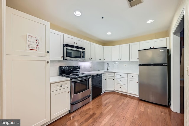 kitchen featuring white cabinetry, sink, stainless steel appliances, and light hardwood / wood-style floors