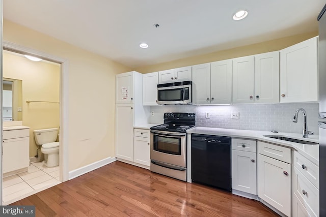 kitchen with light wood-type flooring, appliances with stainless steel finishes, sink, and white cabinets