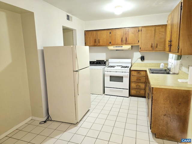 kitchen featuring light tile patterned flooring, white appliances, washer / clothes dryer, and sink