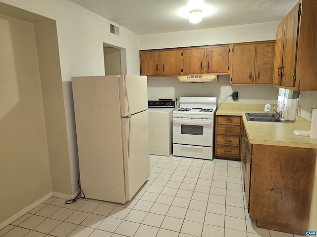 kitchen with light tile patterned floors, white appliances, washer / dryer, and sink