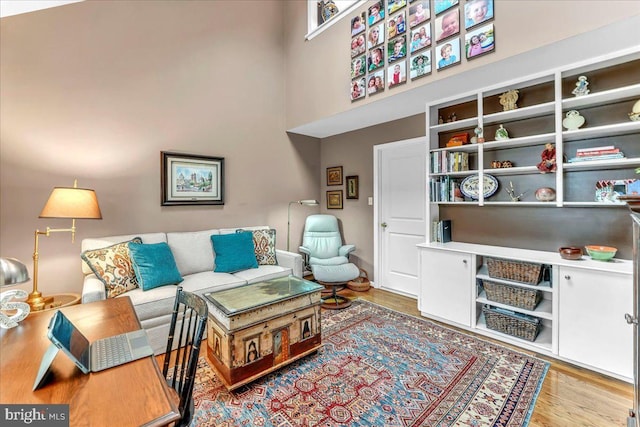 living room with light hardwood / wood-style flooring and a high ceiling