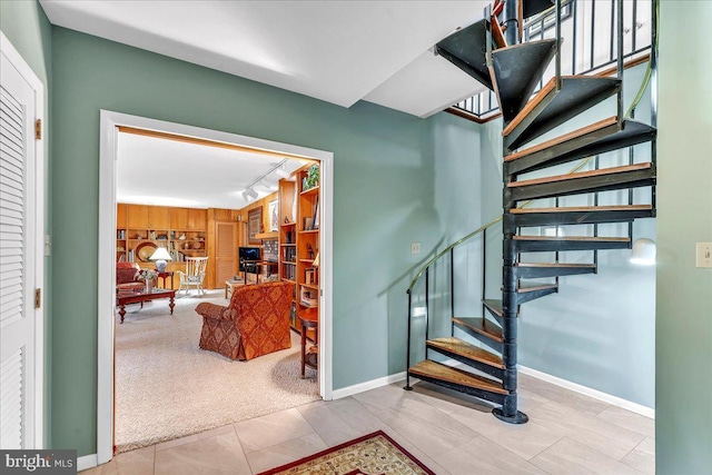 staircase featuring wooden walls, rail lighting, and carpet flooring