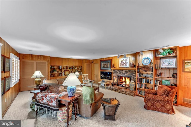 carpeted living room with a brick fireplace and wood walls