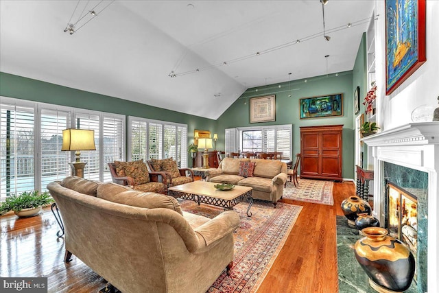 living room featuring a premium fireplace, track lighting, high vaulted ceiling, and light hardwood / wood-style flooring