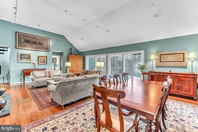 dining area with vaulted ceiling, track lighting, and light wood-type flooring