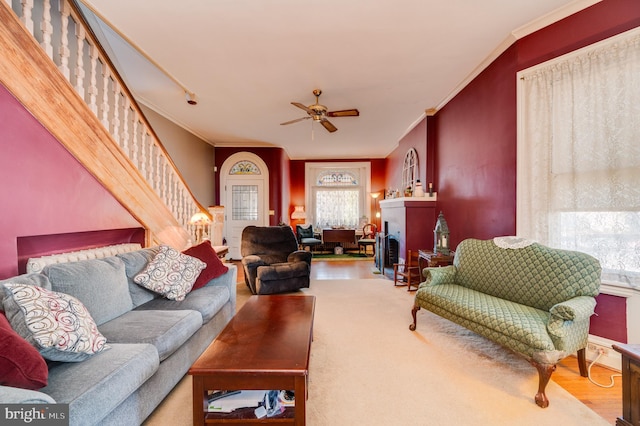 living area featuring ornamental molding, a ceiling fan, and stairs