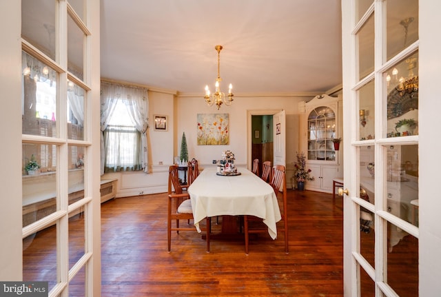 dining room with crown molding, french doors, dark wood finished floors, and an inviting chandelier