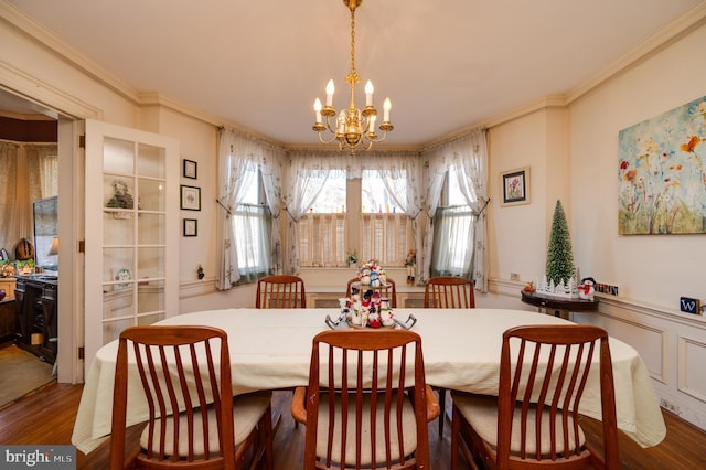 dining area with a chandelier, ornamental molding, a wainscoted wall, and wood finished floors