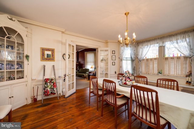 dining space featuring a notable chandelier, ornamental molding, dark wood-style flooring, and french doors