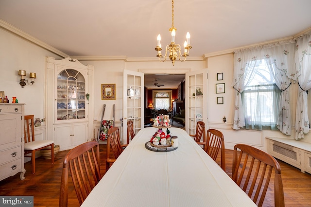 dining room featuring a notable chandelier, crown molding, dark wood-type flooring, and french doors