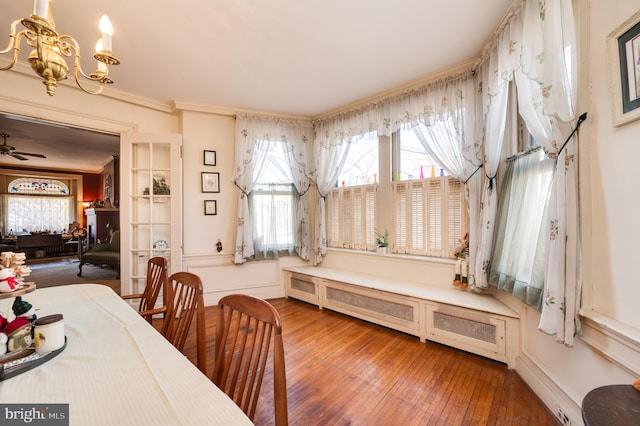 dining area with crown molding, a notable chandelier, and wood finished floors