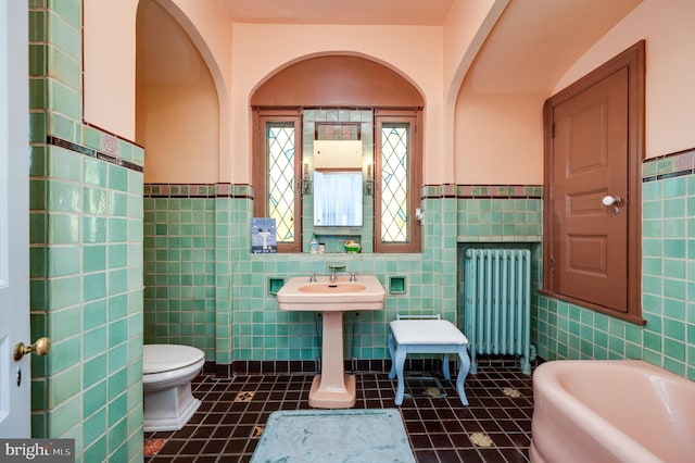 full bathroom with tile patterned flooring, toilet, tile walls, a bath, and radiator