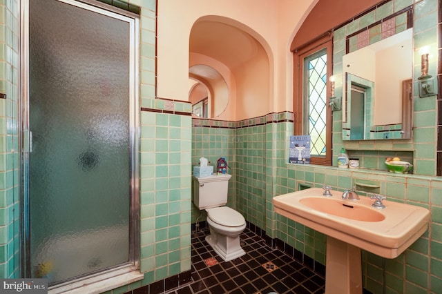 full bathroom featuring a wainscoted wall, tile walls, toilet, a shower stall, and tile patterned flooring