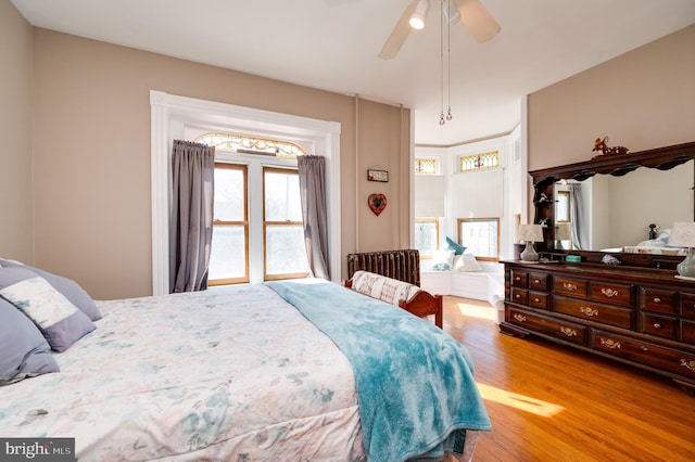 bedroom featuring ceiling fan, light wood finished floors, and radiator