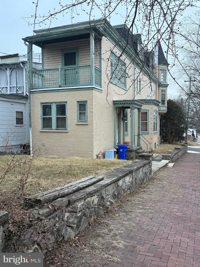 view of side of home with brick siding and a balcony