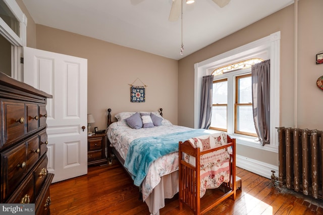 bedroom with ceiling fan, dark wood-style flooring, radiator heating unit, and baseboards