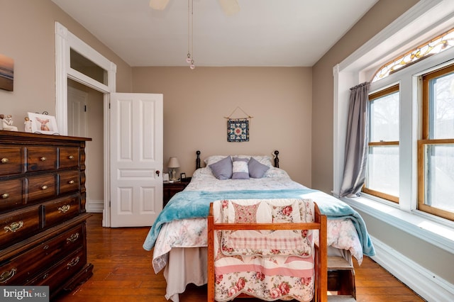 bedroom with ceiling fan, baseboards, and dark wood-style flooring