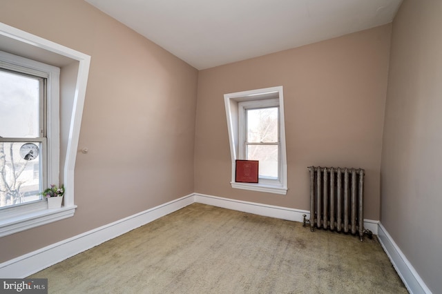 carpeted spare room featuring radiator heating unit and baseboards