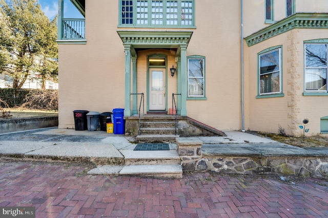 entrance to property featuring a balcony and brick siding