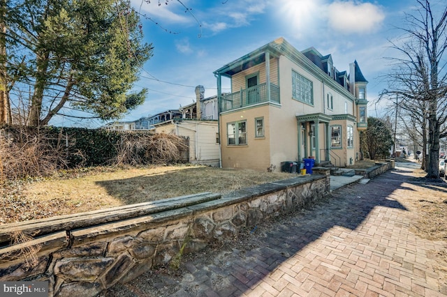 view of home's exterior with a balcony, fence, and stucco siding