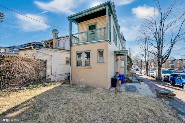 rear view of property featuring a lawn and a balcony