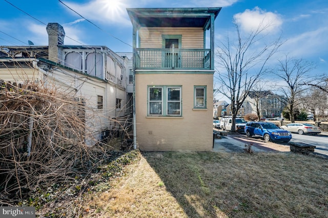 view of home's exterior featuring a lawn and a balcony