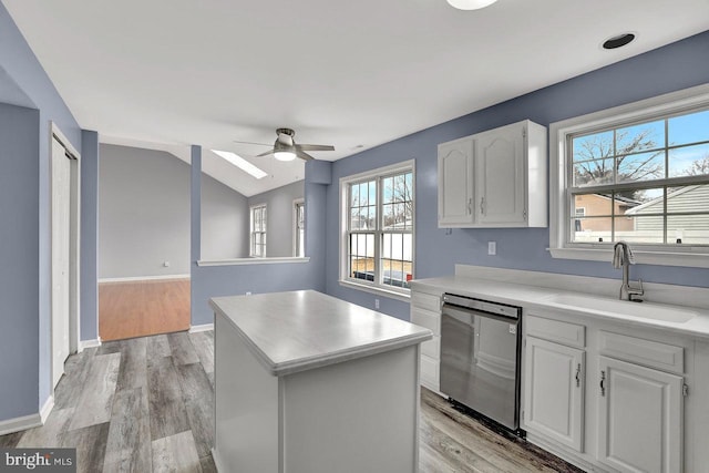 kitchen with white cabinetry, sink, dishwasher, and a kitchen island