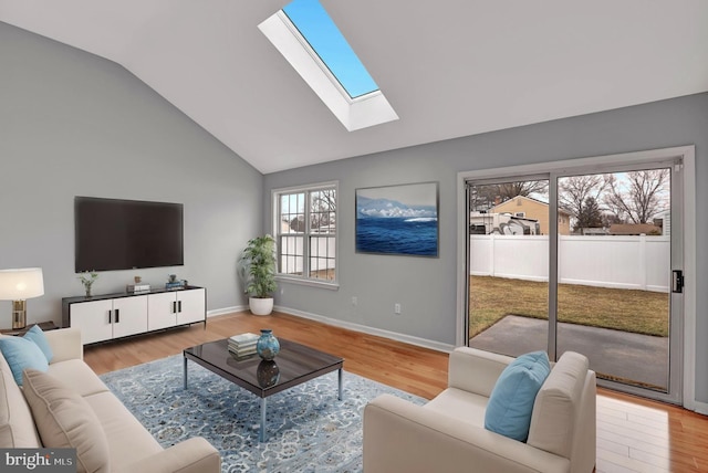 living room featuring lofted ceiling with skylight and light hardwood / wood-style floors