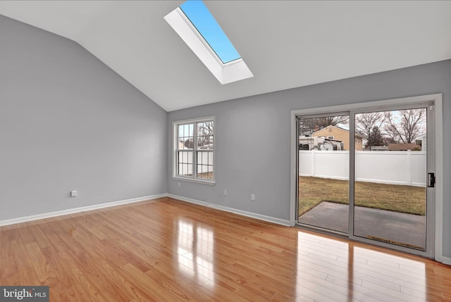 empty room with lofted ceiling with skylight and light wood-type flooring