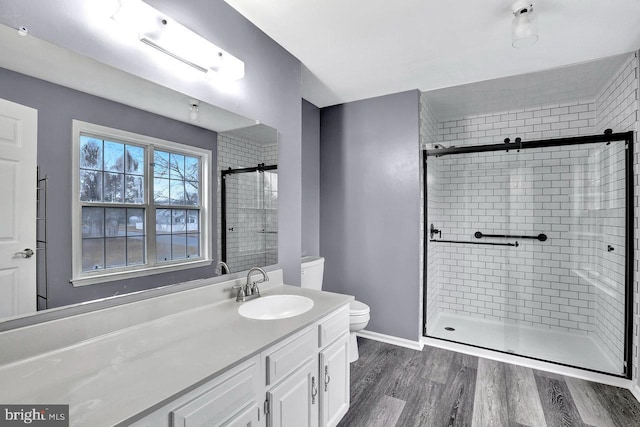 bathroom with vanity, wood-type flooring, a shower with shower door, and toilet