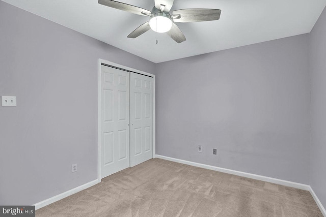 unfurnished bedroom with ceiling fan, light colored carpet, and a closet