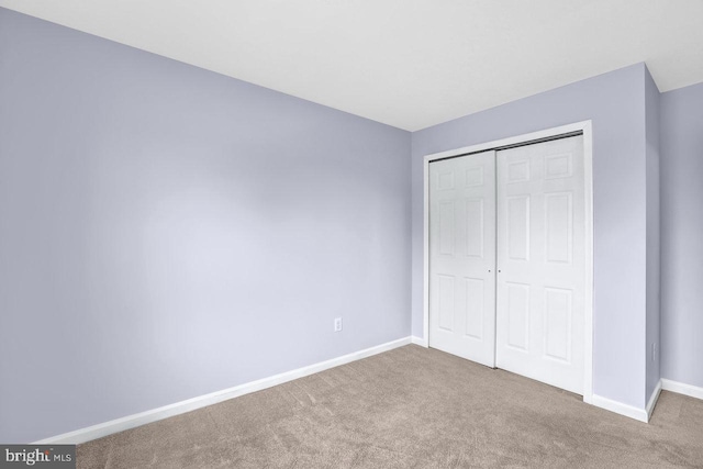 unfurnished bedroom featuring light colored carpet and a closet