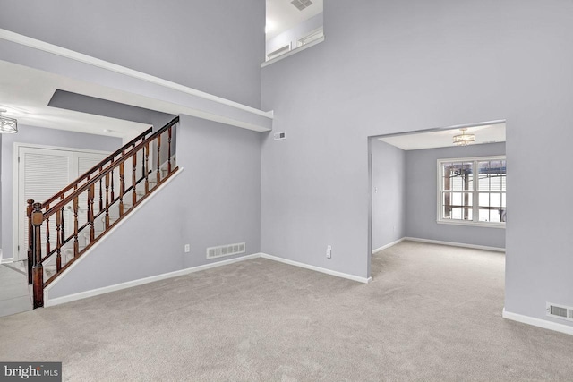 unfurnished living room featuring light colored carpet and a high ceiling