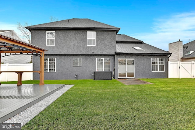 back of property with a gazebo, a wooden deck, and a lawn