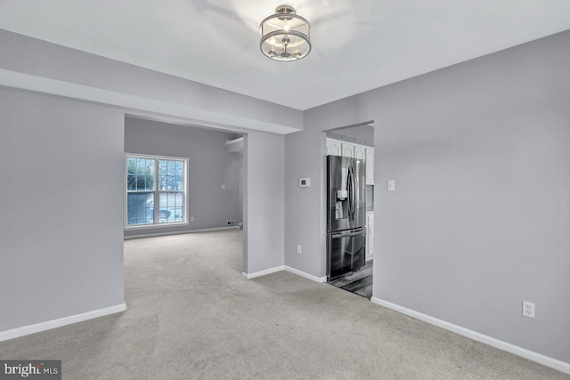 carpeted empty room with a notable chandelier