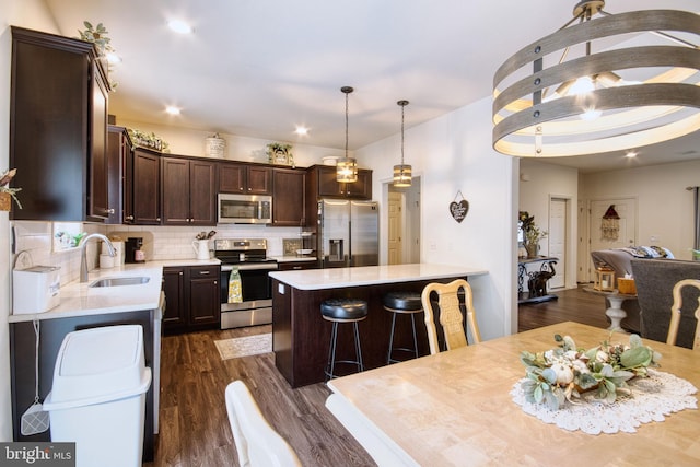 kitchen featuring sink, backsplash, hanging light fixtures, stainless steel appliances, and dark wood-type flooring