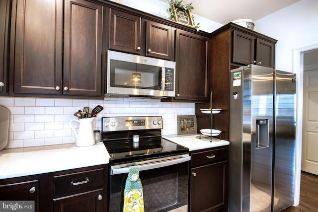 kitchen with stainless steel appliances, dark brown cabinets, dark wood-type flooring, and decorative backsplash