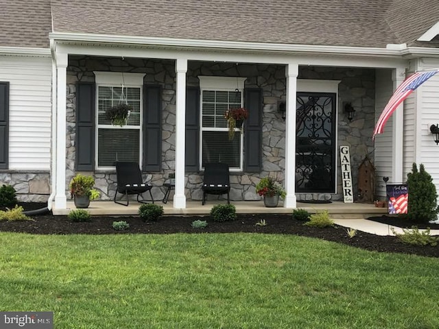 doorway to property featuring covered porch and a lawn