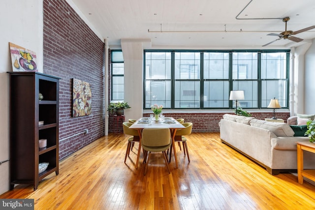 dining room with brick wall, ceiling fan, and light hardwood / wood-style flooring